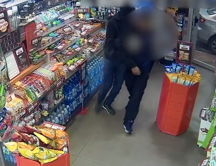 אחד הנאשמים אוחז בעובד בתוך חנות הנוחות שבתחנה