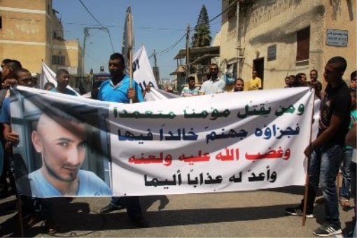 חבריו של הנרצח עם כרזה ותמונתו בהפגנה לאחר הרצח