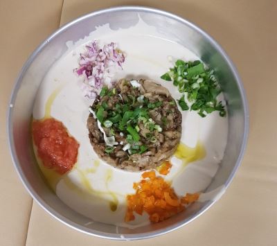 חציל ומעליו בצל ירוק, מסביב טחינה,  מעליה גרידת עגבניות, בצל סגול, גמבה כתומה