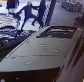 השודד חבוש קסדה (מימין) מתעמת עם עובד בסוכנות הרכבים